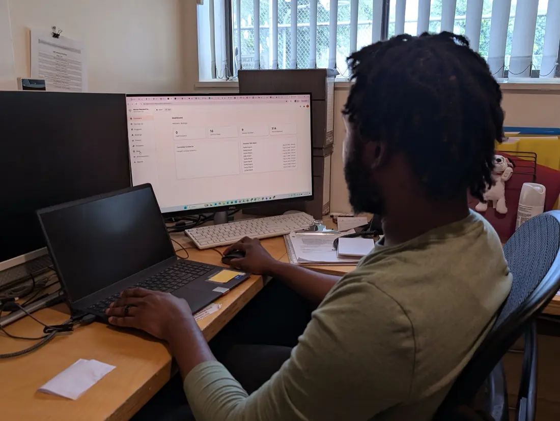 Muzinga at his desk reviewing the reporting dashboard on his monitor